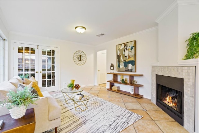 living room featuring french doors, crown molding, a tiled fireplace, and light tile patterned floors