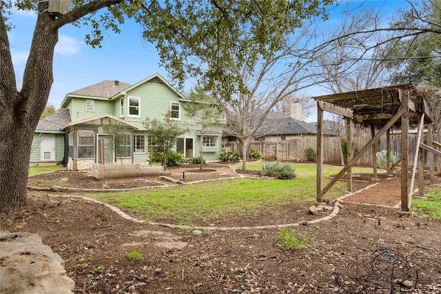 rear view of house with fence, a pergola, and a yard