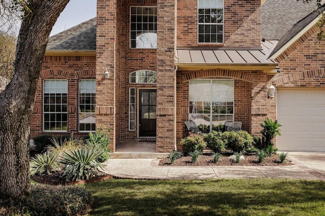 entrance to property with metal roof, covered porch, brick siding, roof with shingles, and a standing seam roof