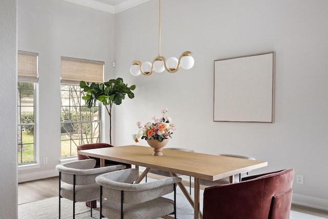 dining space featuring ornamental molding, baseboards, a notable chandelier, and light wood finished floors