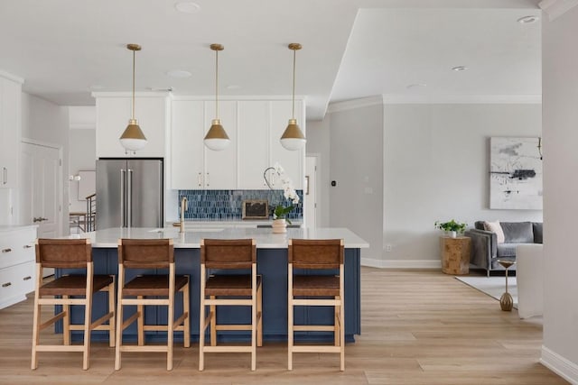 kitchen with high quality fridge, a breakfast bar, light countertops, a center island with sink, and pendant lighting