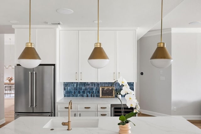 kitchen featuring high quality fridge, light stone counters, visible vents, hanging light fixtures, and decorative backsplash