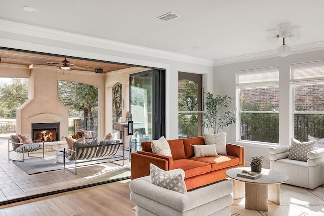 sunroom featuring a warm lit fireplace, ceiling fan, and visible vents