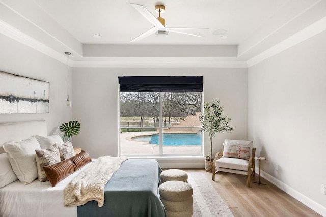 bedroom featuring a raised ceiling, ceiling fan, baseboards, and wood finished floors