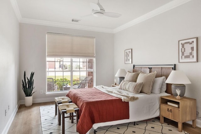 bedroom with light wood-style floors, baseboards, visible vents, and crown molding