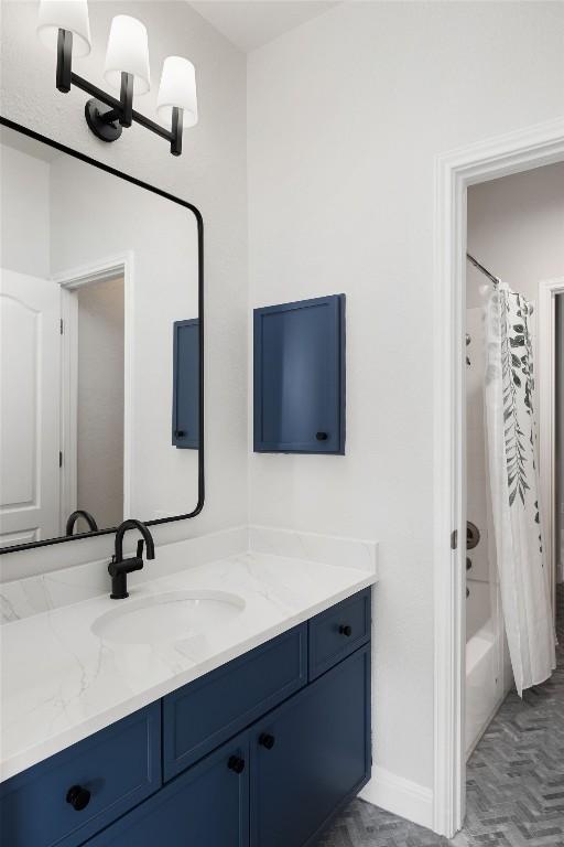 full bath featuring shower / tub combo, baseboards, and vanity