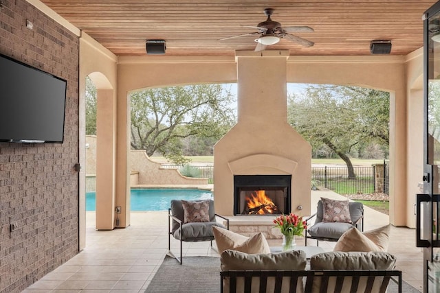 view of patio / terrace featuring an outdoor living space with a fireplace, fence, ceiling fan, and a fenced in pool