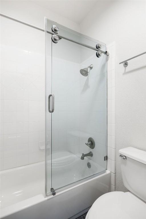 full bathroom featuring combined bath / shower with glass door and toilet