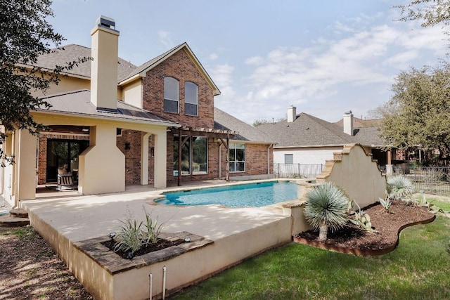 rear view of house with a patio, brick siding, fence, and a fenced in pool