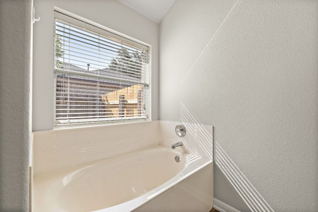 bathroom featuring a textured wall and a bath