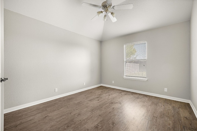 empty room with lofted ceiling, baseboards, a ceiling fan, and dark wood-type flooring