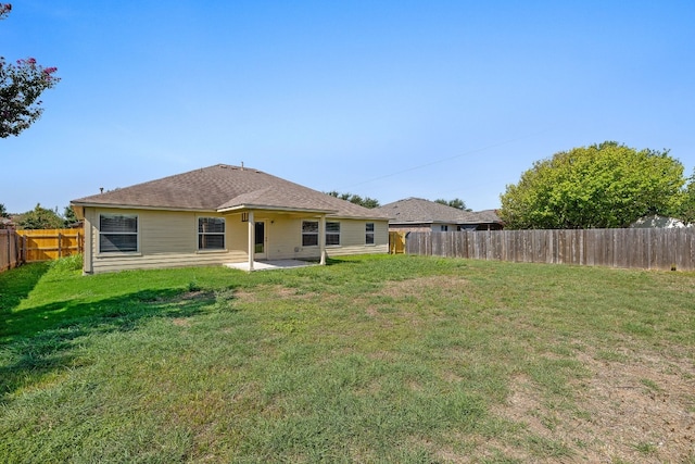 rear view of house with a fenced backyard, a lawn, and a patio