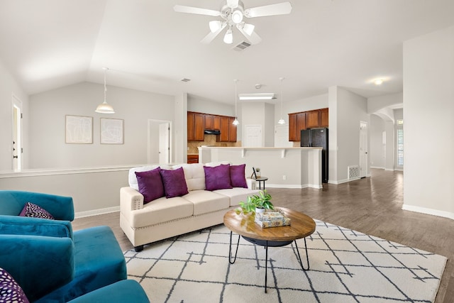 living room featuring light wood-type flooring, visible vents, vaulted ceiling, and arched walkways