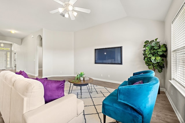 living room featuring arched walkways, baseboards, and wood finished floors