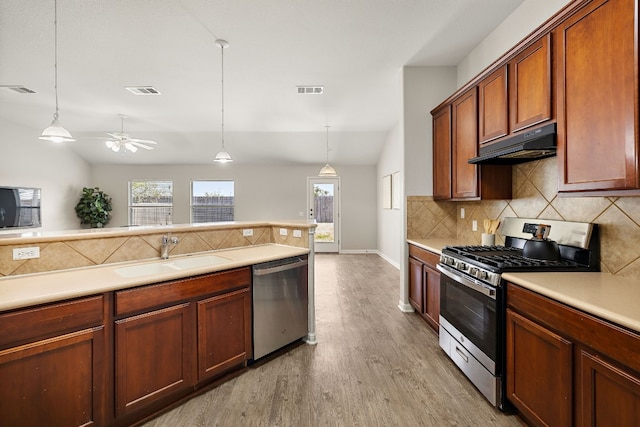 kitchen with appliances with stainless steel finishes, light countertops, a sink, and under cabinet range hood