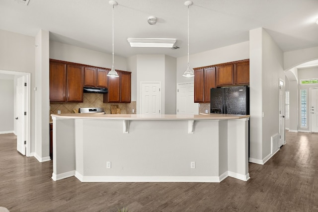 kitchen with light countertops, a breakfast bar, hanging light fixtures, and freestanding refrigerator
