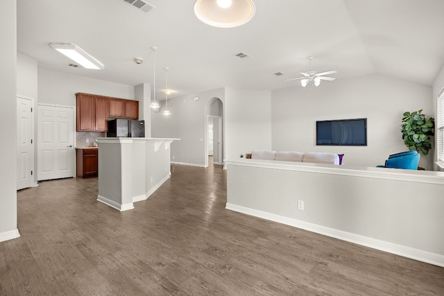 kitchen featuring arched walkways, a kitchen island, open floor plan, light countertops, and freestanding refrigerator