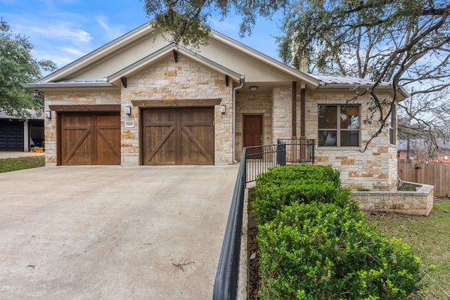 view of front of home with a garage, concrete driveway, metal roof, and fence