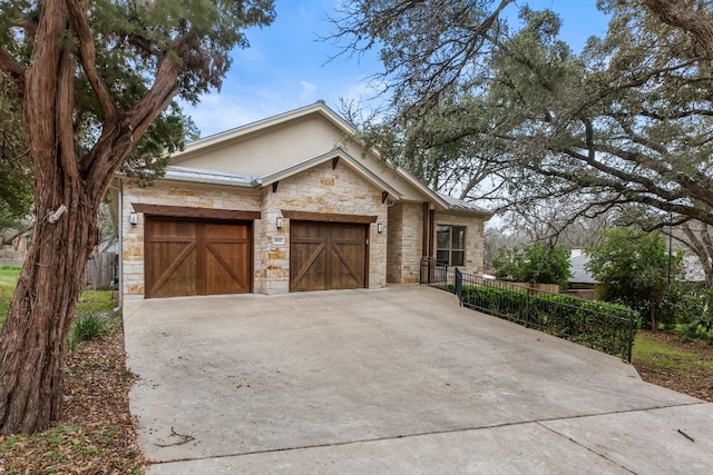 view of front of house featuring stucco siding, concrete driveway, an attached garage, fence, and stone siding