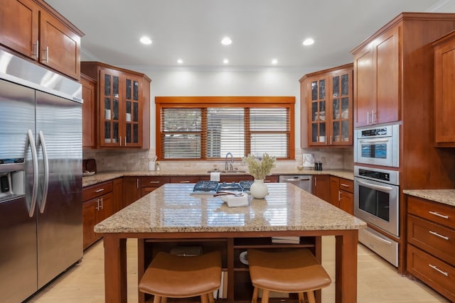 kitchen featuring glass insert cabinets, appliances with stainless steel finishes, a breakfast bar, and a warming drawer