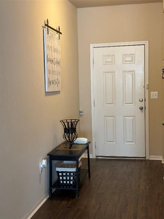 doorway featuring dark wood-type flooring and baseboards