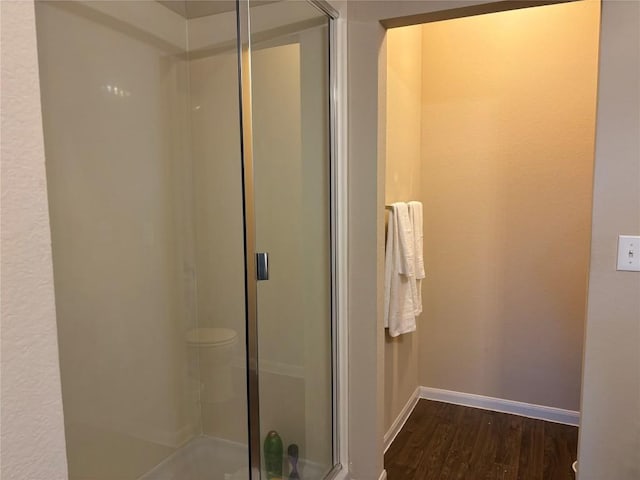 full bath featuring a stall shower, wood finished floors, and baseboards