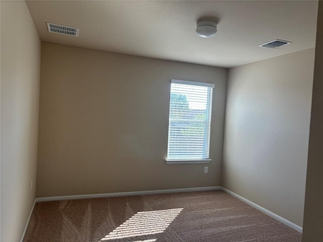 empty room with carpet, visible vents, and baseboards