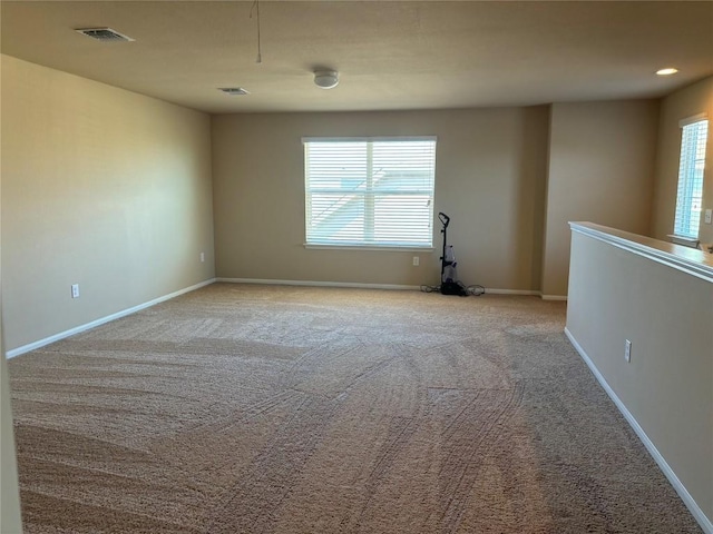 unfurnished room featuring light carpet, plenty of natural light, visible vents, and baseboards