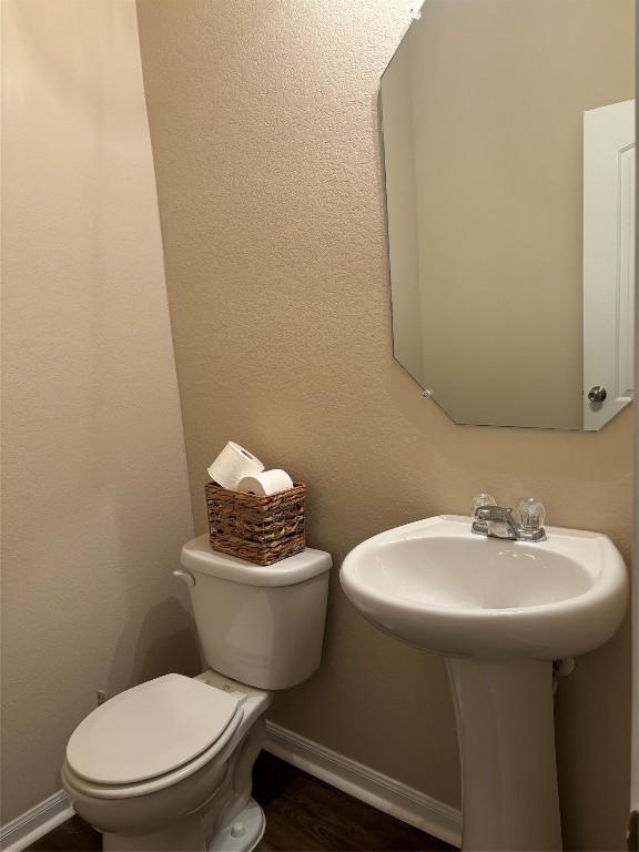 bathroom featuring toilet, baseboards, and wood finished floors