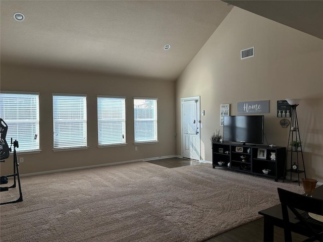 carpeted living area with high vaulted ceiling, baseboards, and visible vents