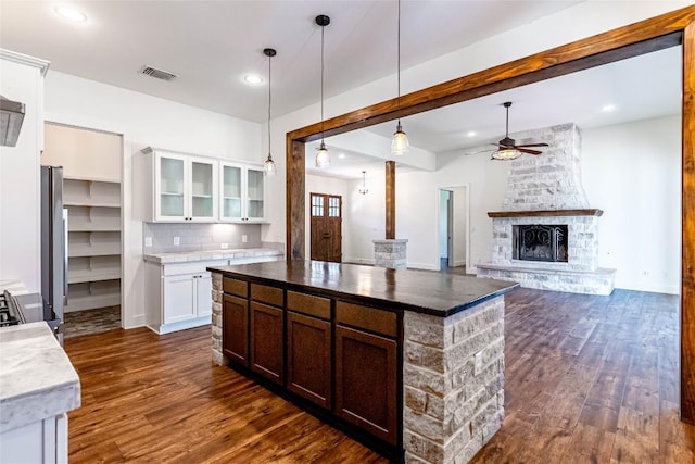 kitchen featuring dark wood finished floors, hanging light fixtures, glass insert cabinets, open floor plan, and white cabinetry