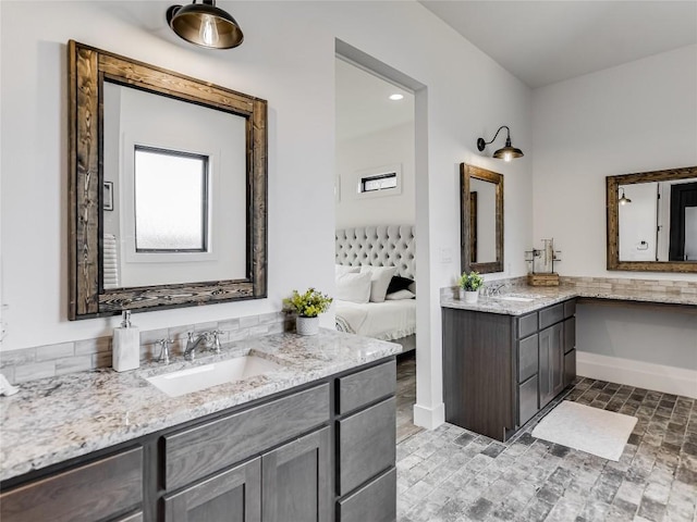 full bath with a sink, two vanities, ensuite bath, and baseboards