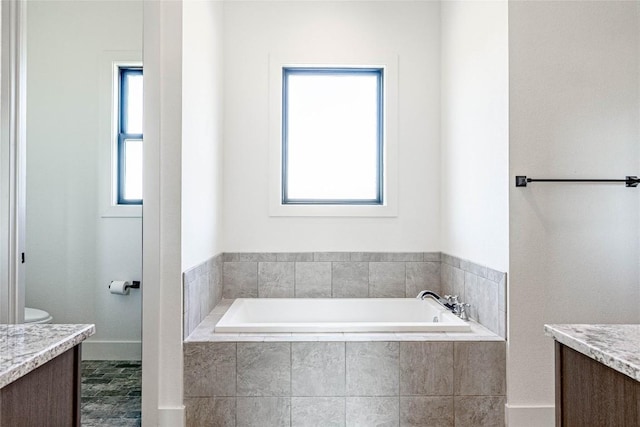 bathroom with a garden tub, vanity, and toilet