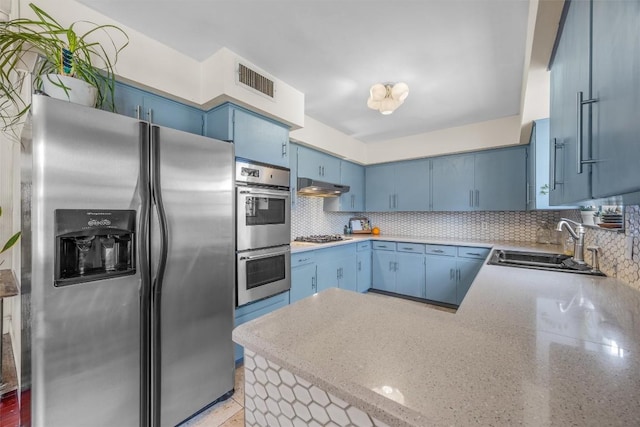 4608 Arapahoe Trl, Austin, TX 78745 - kitchen featuring stainless steel appliances, blue cabinets, under cabinet range hood, and tasteful backsplash