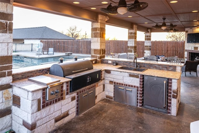 view of patio / terrace with grilling area, a ceiling fan, a sink, exterior kitchen, and a fenced backyard