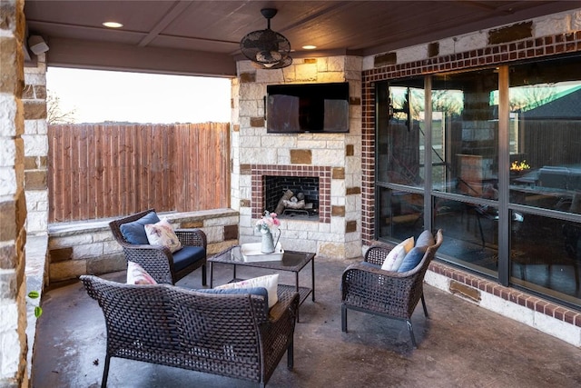 view of patio / terrace featuring a ceiling fan, an outdoor stone fireplace, and fence