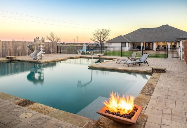 view of pool with a fenced backyard, a fire pit, and a water slide