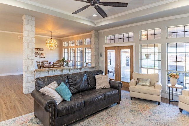 living area with crown molding, light wood finished floors, and ornate columns