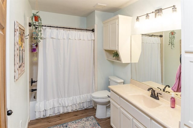 full bath featuring visible vents, toilet, wood finished floors, shower / bath combo with shower curtain, and vanity