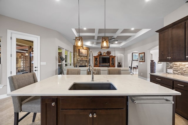 kitchen featuring coffered ceiling, a breakfast bar, open floor plan, a kitchen island with sink, and a sink