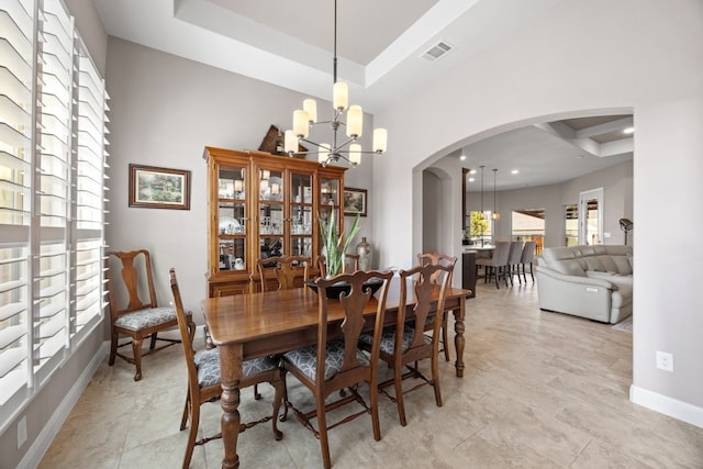 dining room featuring a tray ceiling, visible vents, and a notable chandelier