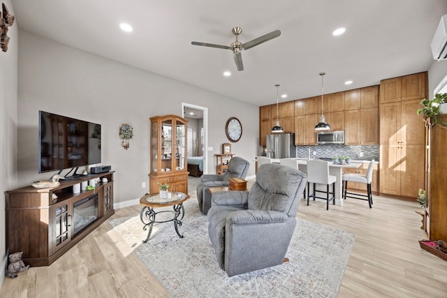 living area with baseboards, a ceiling fan, light wood-style flooring, and recessed lighting