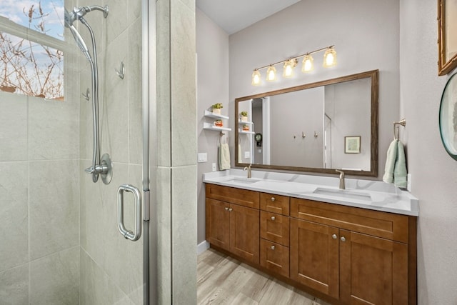 bathroom featuring double vanity, wood finished floors, a stall shower, and a sink