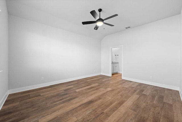 empty room featuring baseboards, visible vents, ceiling fan, wood finished floors, and vaulted ceiling