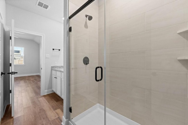 full bathroom featuring lofted ceiling, visible vents, a stall shower, vanity, and wood finished floors