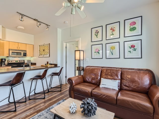 living room with dark wood-type flooring, rail lighting, and a ceiling fan