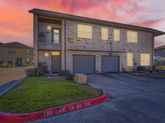 1201 Grove Blvd Unit 2803, Austin, TX 78741 - view of property featuring asphalt driveway, stone siding, a lawn, and a garage