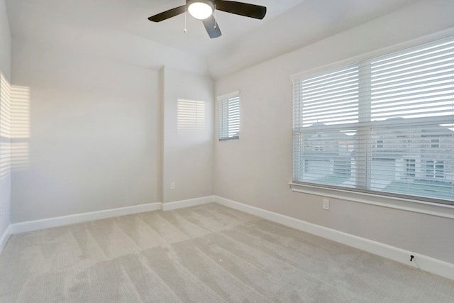 empty room with a ceiling fan, lofted ceiling, light carpet, and baseboards