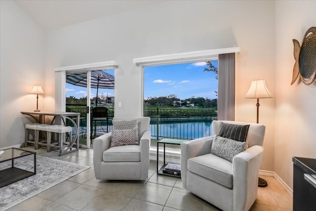 living area featuring a water view, baseboards, and light tile patterned floors