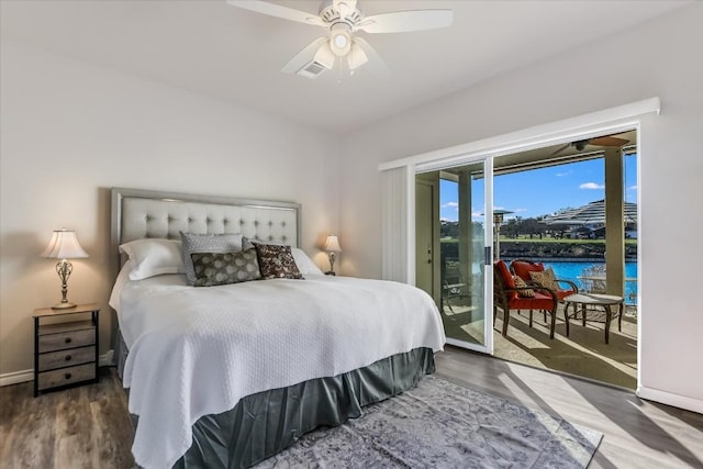 bedroom featuring a water view, access to exterior, baseboards, and wood finished floors